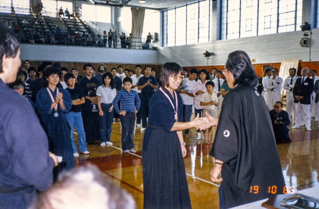 Jean Kodama, receiving her 1st-place medal at the All California Championships in 1986. California only held two state championships, in 1986 and 1989. She won first place both times. She was equally proud of her wins here as she was of her national medals due to the intense caliber of competition in California. To date, California’s men and women teams have swept all team divisions at the U.S. Championships