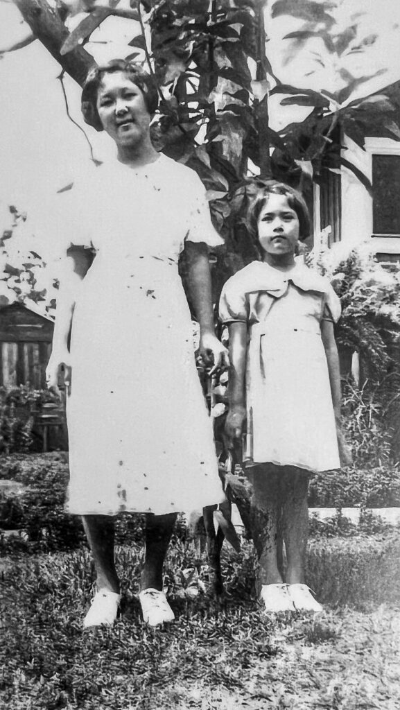 Saiki (far right) and her older sister standing in their front yard.